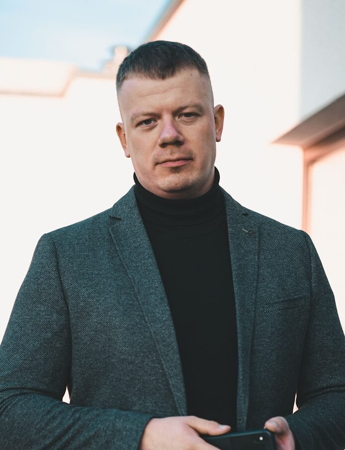 man in black suit holding black smartphone